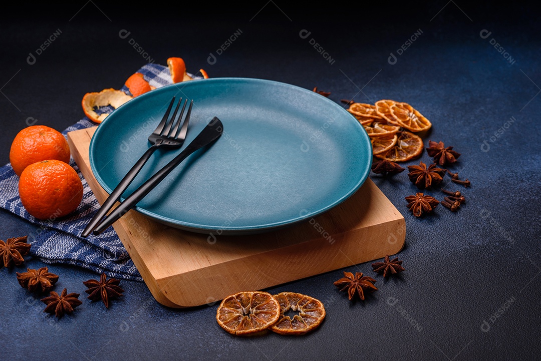 Linda composição festiva de Natal de um prato vazio, tangerina, pão de gengibre e anis estrelado em um fundo escuro e texturizado