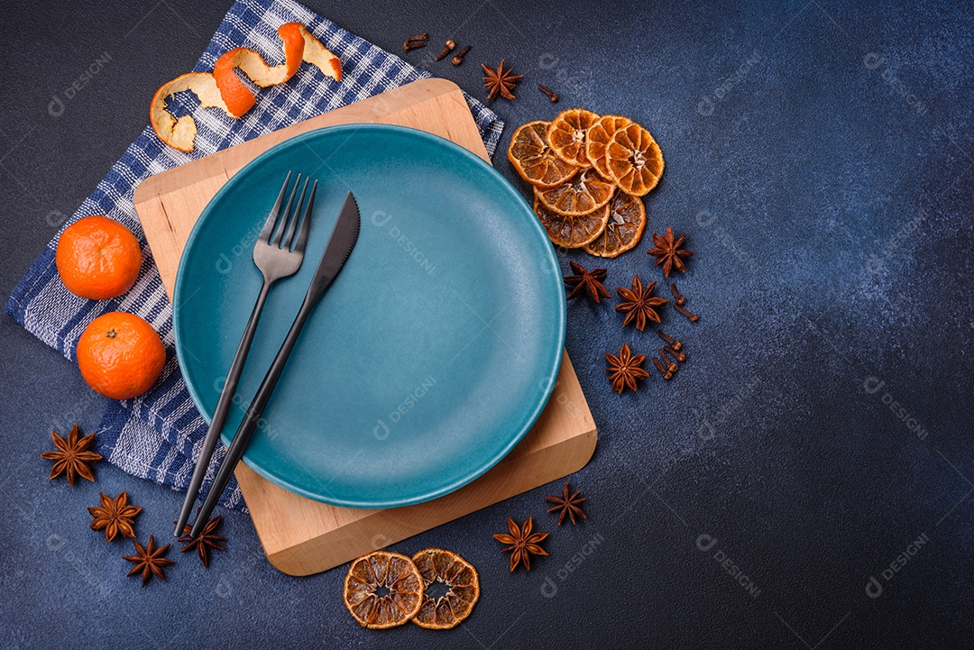 Linda composição festiva de Natal de um prato vazio, tangerina, pão de gengibre e anis estrelado em um fundo escuro e texturizado