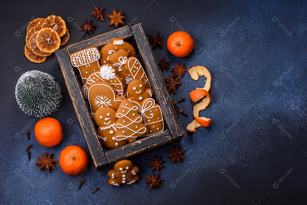 Linda composição festiva de Natal de tangerinas, pão de gengibre e anis estrelado em um fundo escuro e texturizado