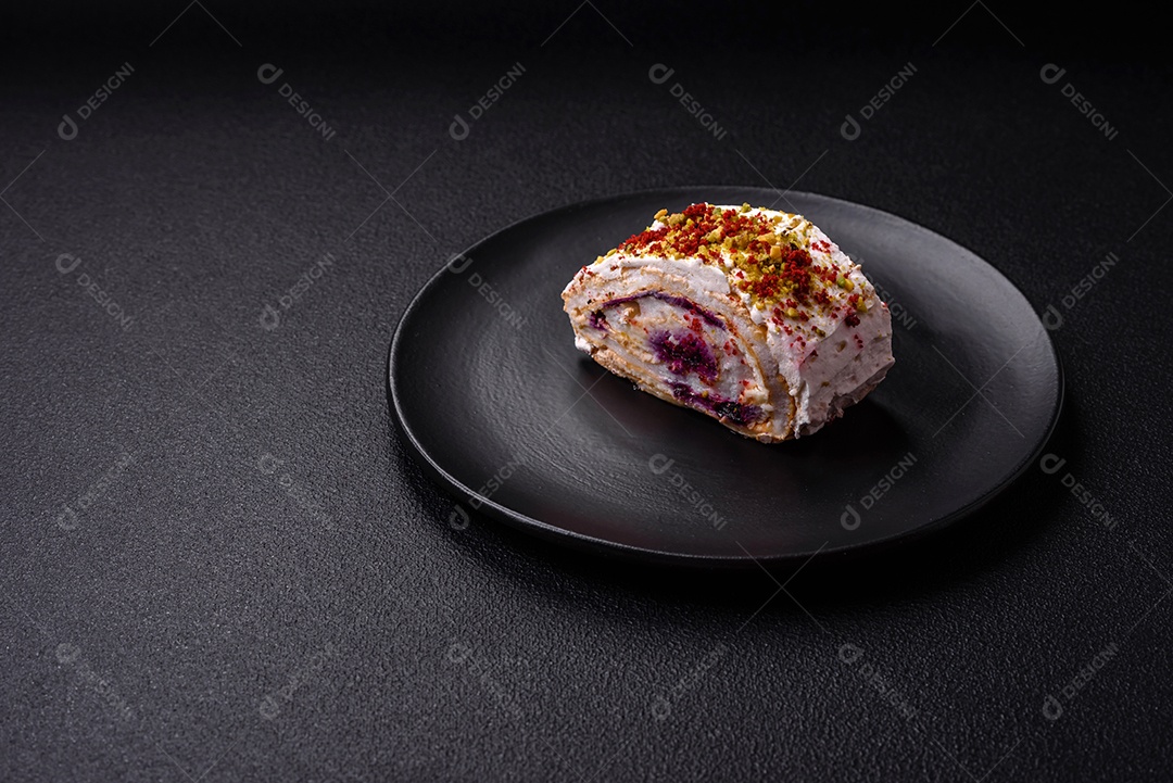 Um pedaço de delicioso rolo de merengue doce com queijo mascarpone, frutas e amêndoas sobre um fundo escuro de concreto