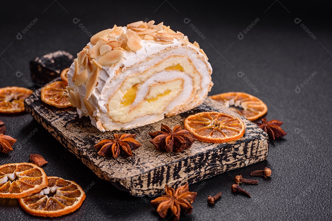 Um pedaço de delicioso rolo de merengue doce com queijo mascarpone, frutas e amêndoas sobre um fundo escuro de concreto