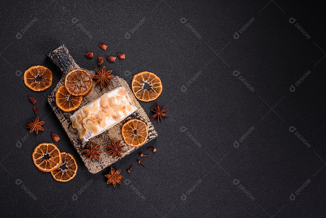 Um pedaço de delicioso rolo de merengue doce com queijo mascarpone, frutas e amêndoas sobre um fundo escuro de concreto