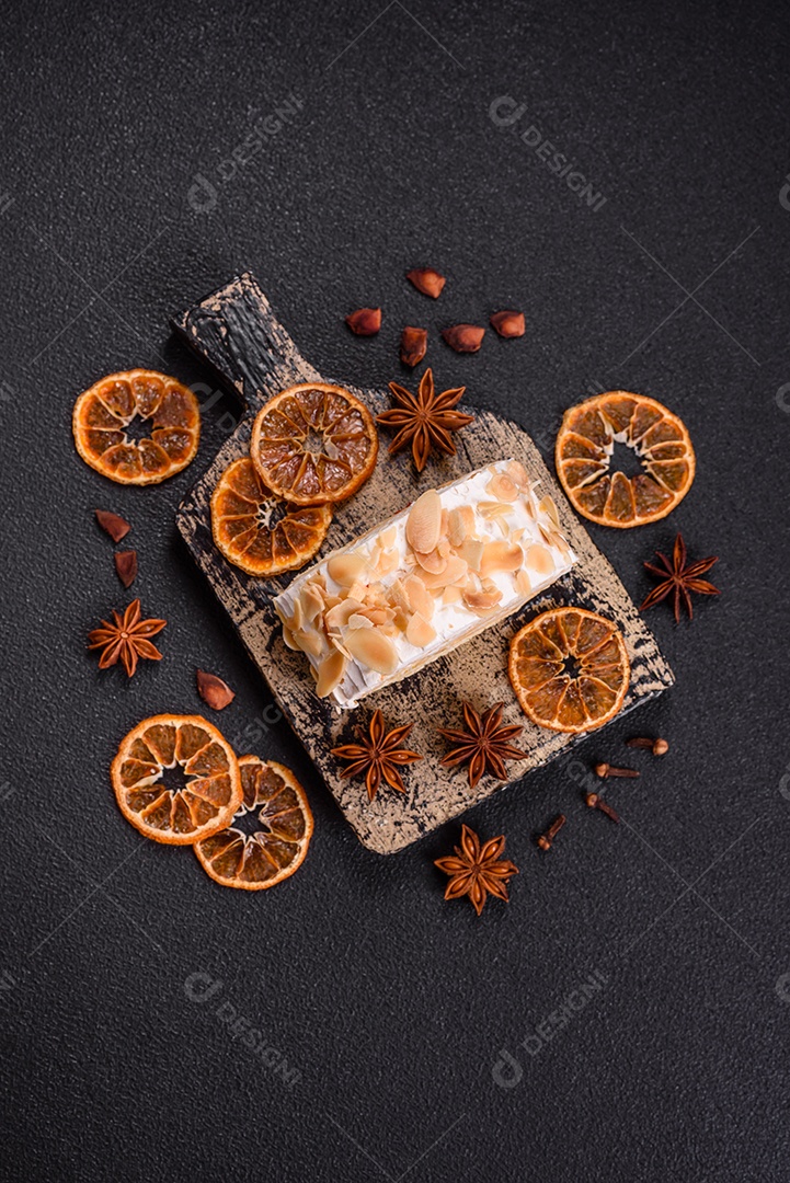 Um pedaço de delicioso rolo de merengue doce com queijo mascarpone, frutas e amêndoas sobre um fundo escuro de concreto