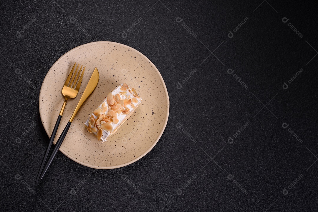 Um pedaço de delicioso rolo de merengue doce com queijo mascarpone, frutas e amêndoas sobre um fundo escuro de concreto