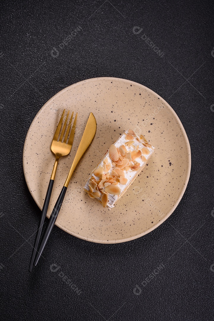 Um pedaço de delicioso rolo de merengue doce com queijo mascarpone, frutas e amêndoas sobre um fundo escuro de concreto