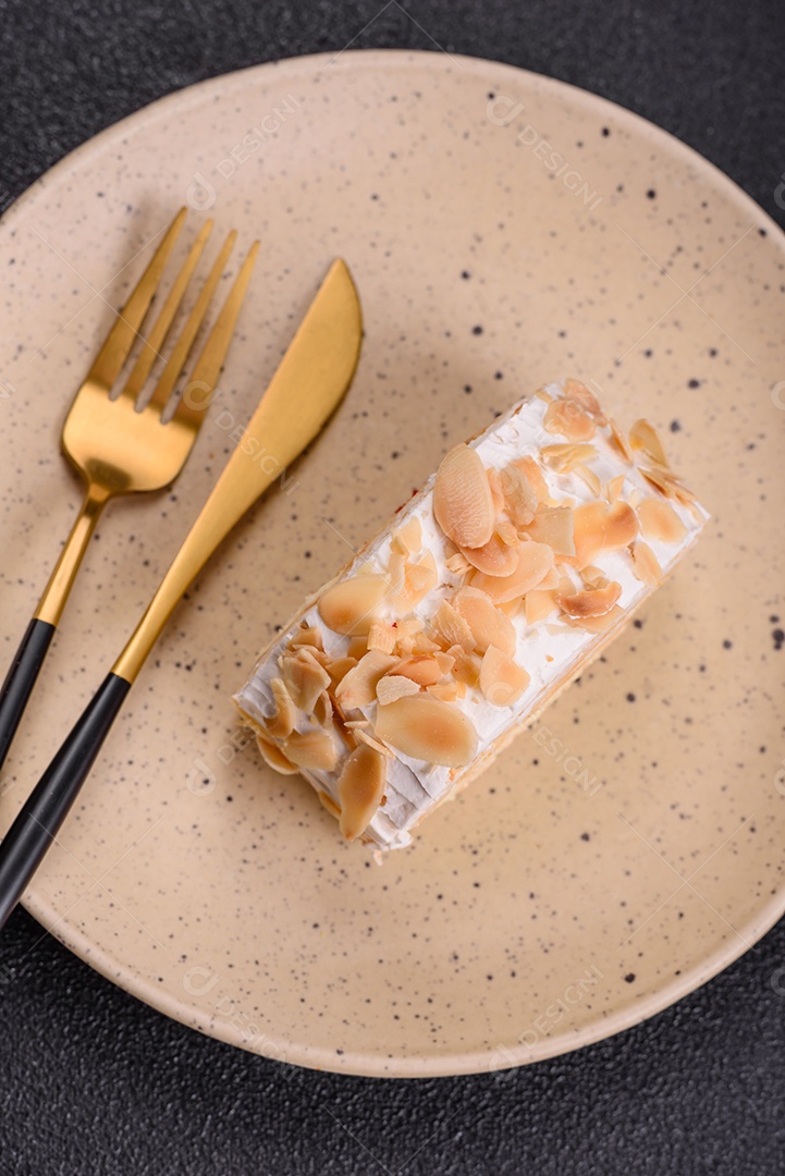 Um pedaço de delicioso rolo de merengue doce com queijo mascarpone, frutas e amêndoas sobre um fundo escuro de concreto