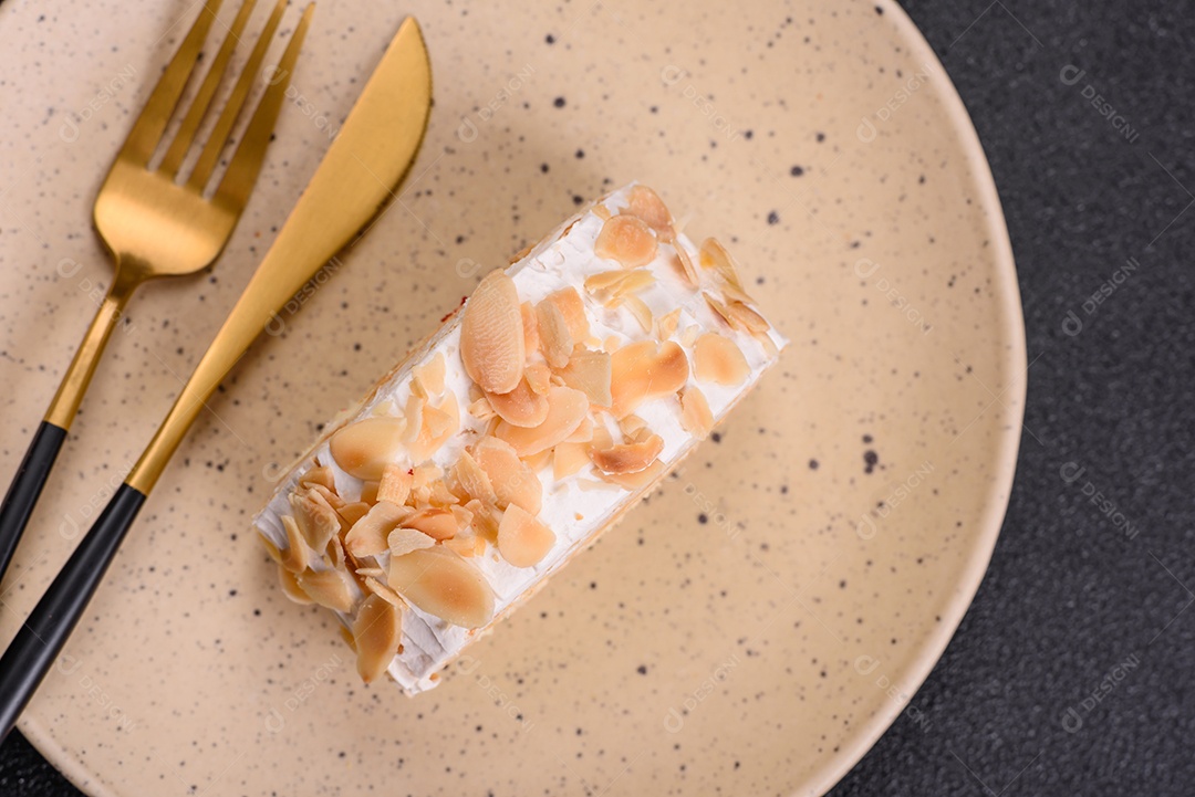 Um pedaço de delicioso rolo de merengue doce com queijo mascarpone, frutas e amêndoas sobre um fundo escuro de concreto