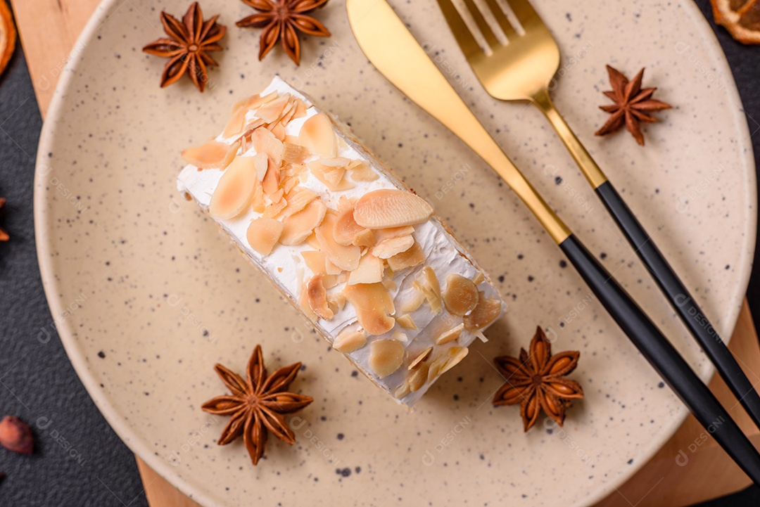 Um pedaço de delicioso rolo de merengue doce com queijo mascarpone, frutas e amêndoas sobre um fundo escuro de concreto