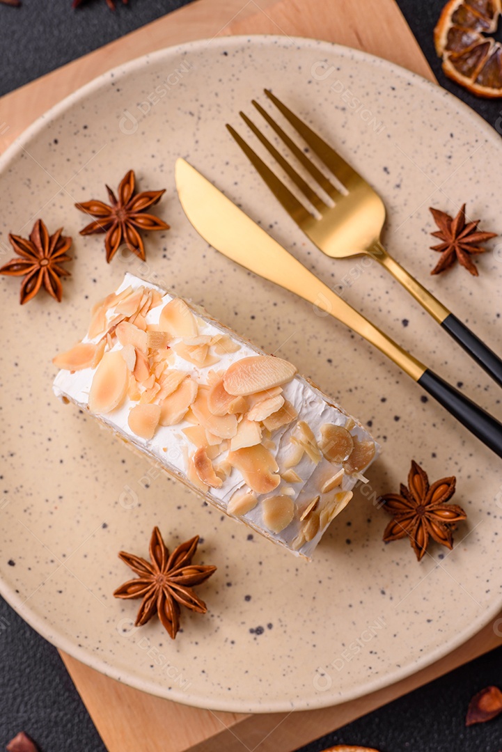 Um pedaço de delicioso rolo de merengue doce com queijo mascarpone, frutas e amêndoas sobre um fundo escuro de concreto