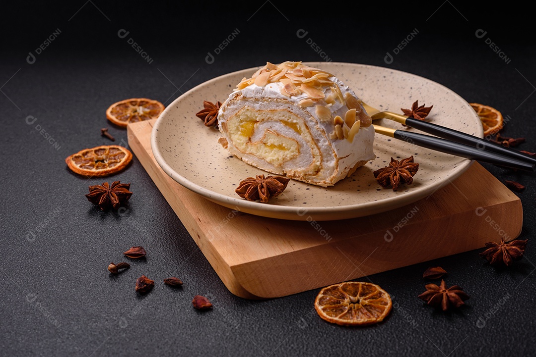 Um pedaço de delicioso rolo de merengue doce com queijo mascarpone, frutas e amêndoas sobre um fundo escuro de concreto