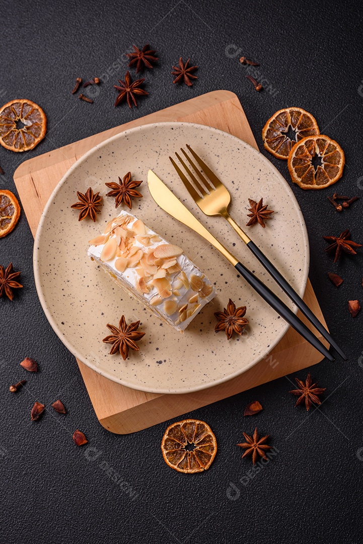 Um pedaço de delicioso rolo de merengue doce com queijo mascarpone, frutas e amêndoas sobre um fundo escuro de concreto