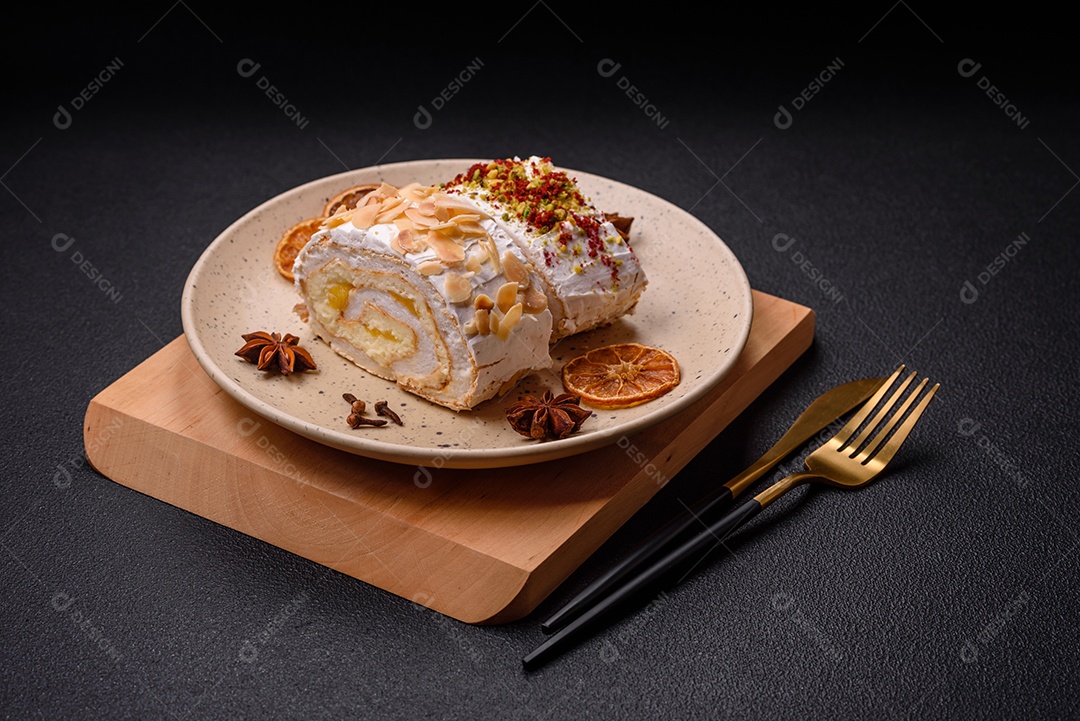 Um pedaço de delicioso rolo de merengue doce com queijo mascarpone, frutas e amêndoas sobre um fundo escuro de concreto