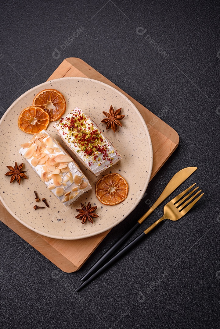 Um pedaço de delicioso rolo de merengue doce com queijo mascarpone, frutas e amêndoas sobre um fundo escuro de concreto