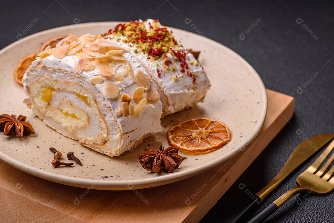 Um pedaço de delicioso rolo de merengue doce com queijo mascarpone, frutas e amêndoas sobre um fundo escuro de concreto