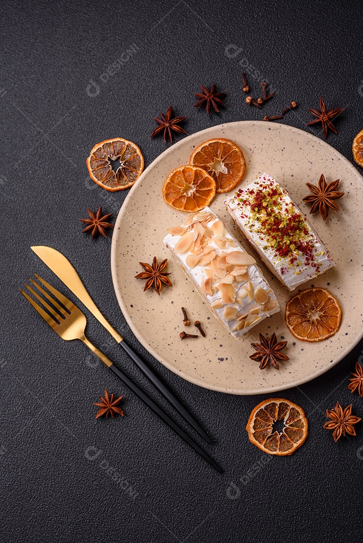 Um pedaço de delicioso rolo de merengue doce com queijo mascarpone, frutas e amêndoas sobre um fundo escuro de concreto