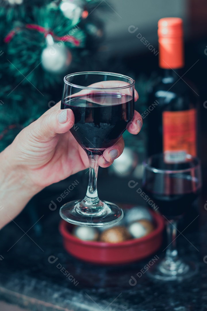 Segurando uma taça de vinho com árvore de Natal no fundo do quintal