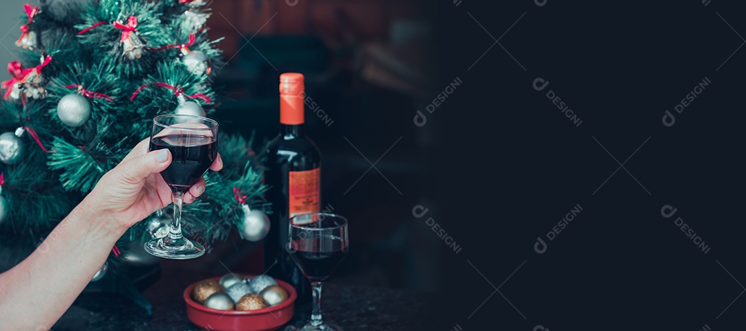 Segurando uma taça de vinho com árvore de Natal no fundo do quintal