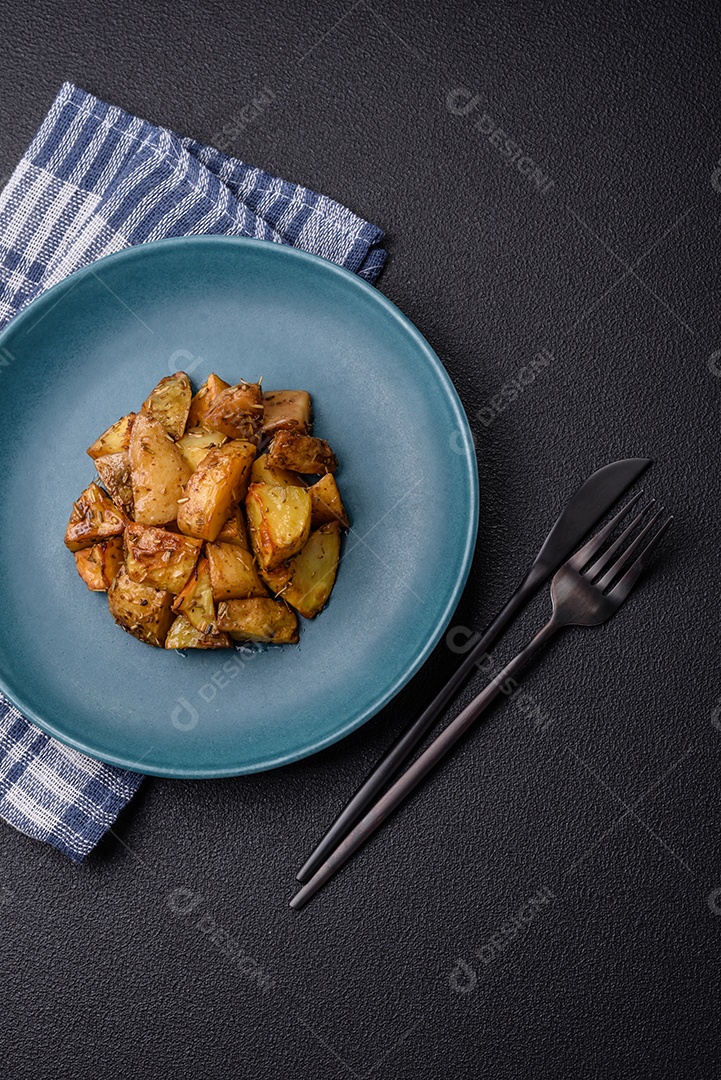 Deliciosas fatias de batata frita crocante com sal, especiarias e ervas sobre um fundo esc