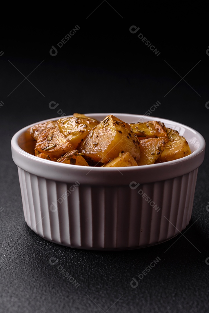 Deliciosas fatias de batata frita crocante com sal, especiarias e ervas sobre um fundo esc