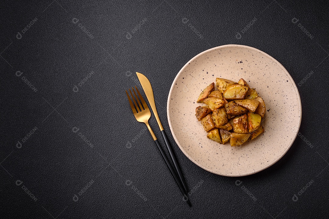Deliciosas fatias de batata frita crocante com sal, especiarias e ervas sobre um fundo esc