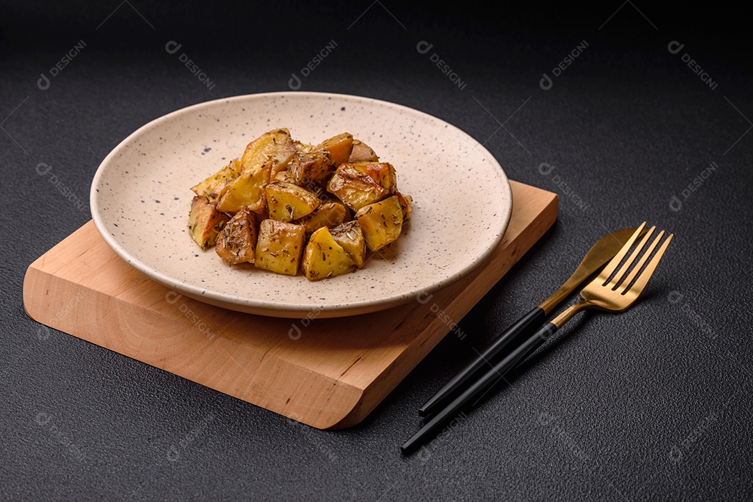 Deliciosas fatias de batata frita crocante com sal, especiarias e ervas sobre um fundo esc