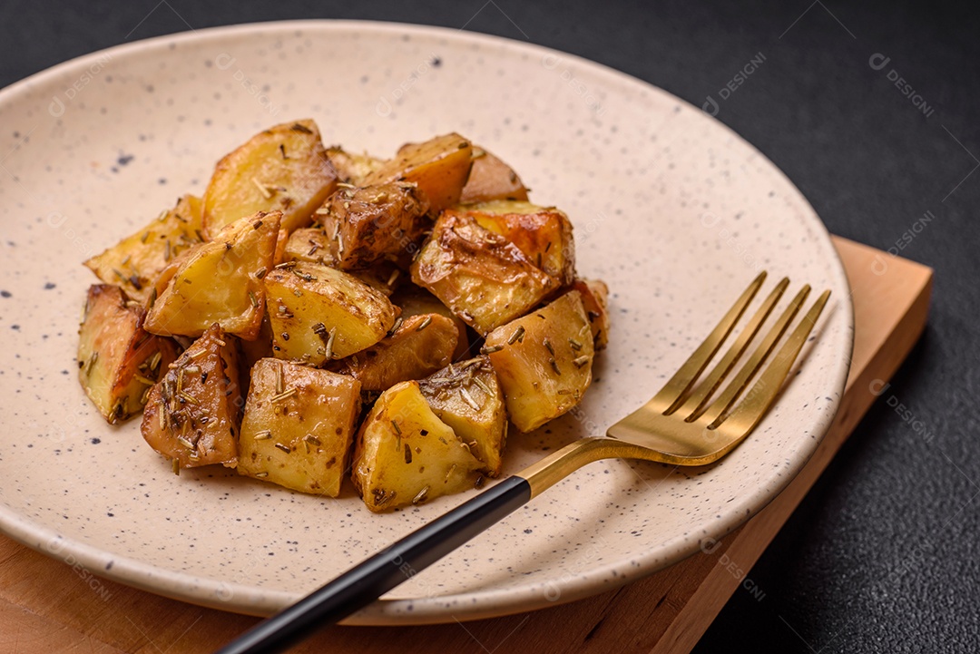 Deliciosas fatias de batata frita crocante com sal, especiarias e ervas sobre um fundo escuro de concreto