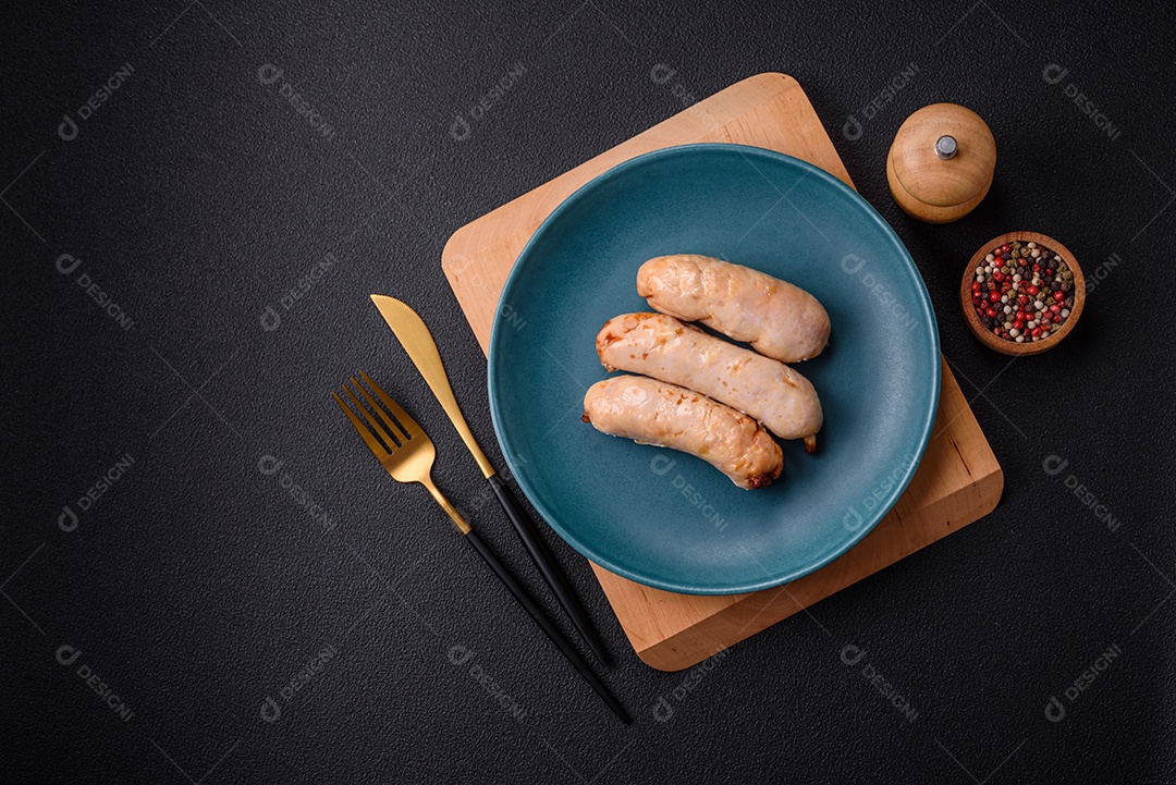 Deliciosos enchidos de frango ou porco grelhados com sal, especiarias e ervas sobre um fundo escuro de concreto