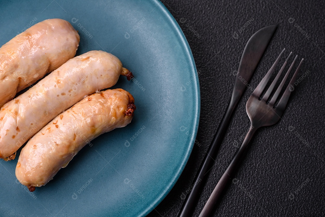 Deliciosos enchidos de frango ou porco grelhados com sal, especiarias e ervas sobre um fundo escuro de concreto