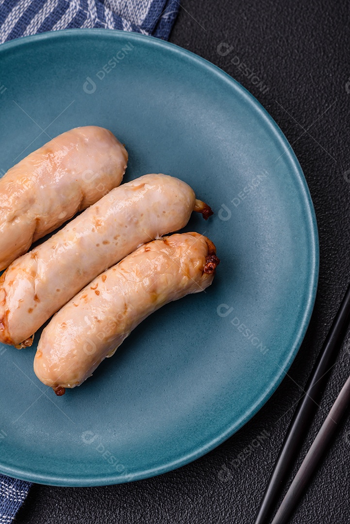 Deliciosos enchidos de frango ou porco grelhados com sal, especiarias e ervas sobre um fundo escuro de concreto