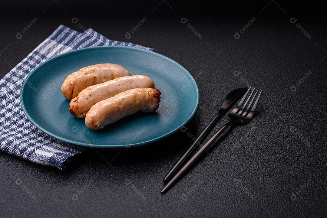 Deliciosos enchidos de frango ou porco grelhados com sal, especiarias e ervas sobre um fundo escuro de concreto