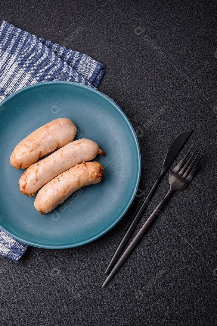 Deliciosos enchidos de frango ou porco grelhados com sal, especiarias e ervas sobre um fundo escuro de concreto