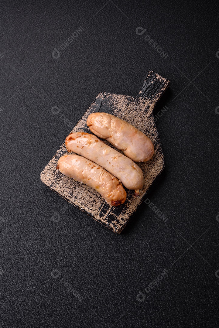 Deliciosos enchidos de frango ou porco grelhados com sal, especiarias e ervas sobre um fundo escuro de concreto