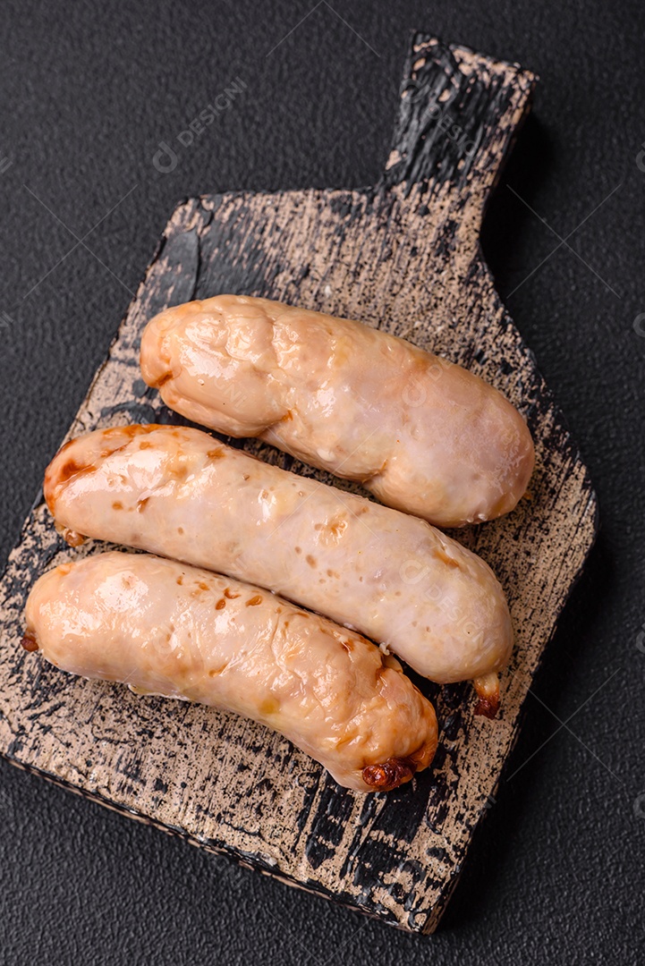 Deliciosos enchidos de frango ou porco grelhados com sal, especiarias e ervas sobre um fundo escuro de concreto