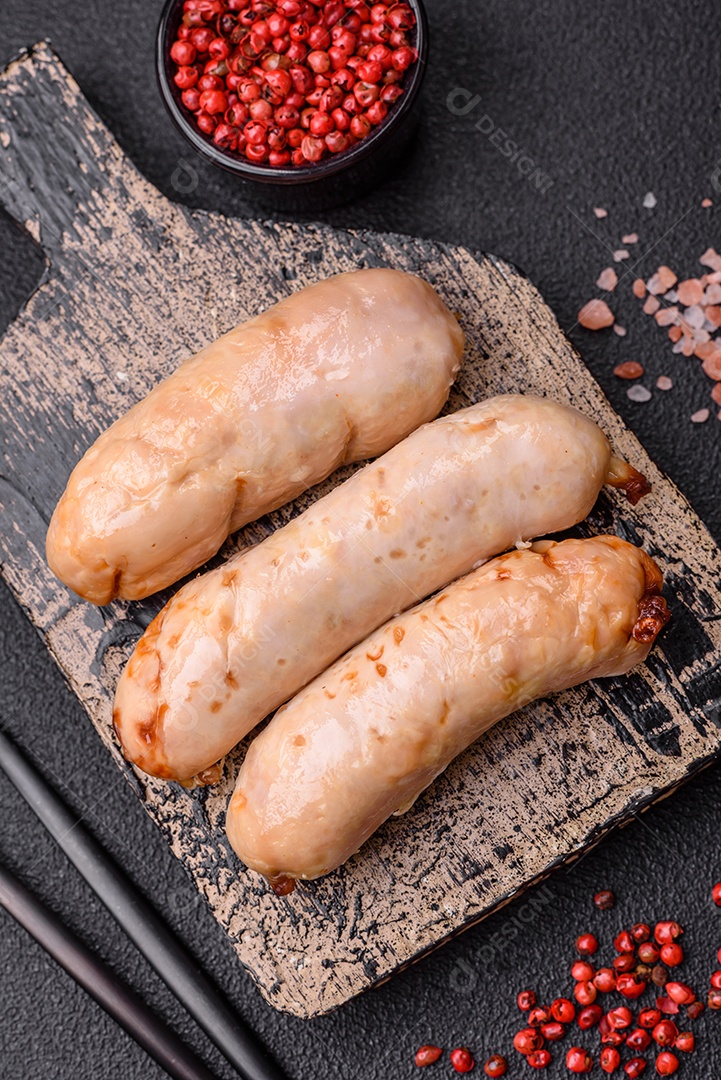 Deliciosos enchidos de frango ou porco grelhados com sal, especiarias e ervas sobre um fundo escuro de concreto