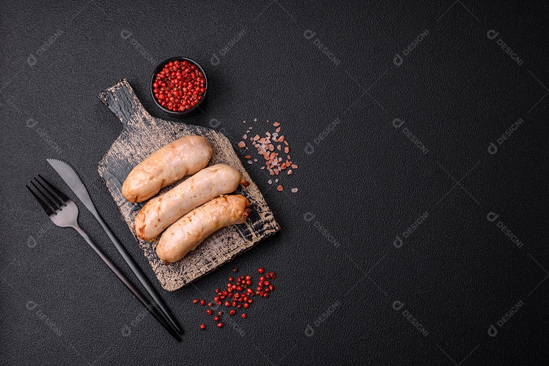 Deliciosos enchidos de frango ou porco grelhados com sal, especiarias e ervas sobre um fundo escuro de concreto