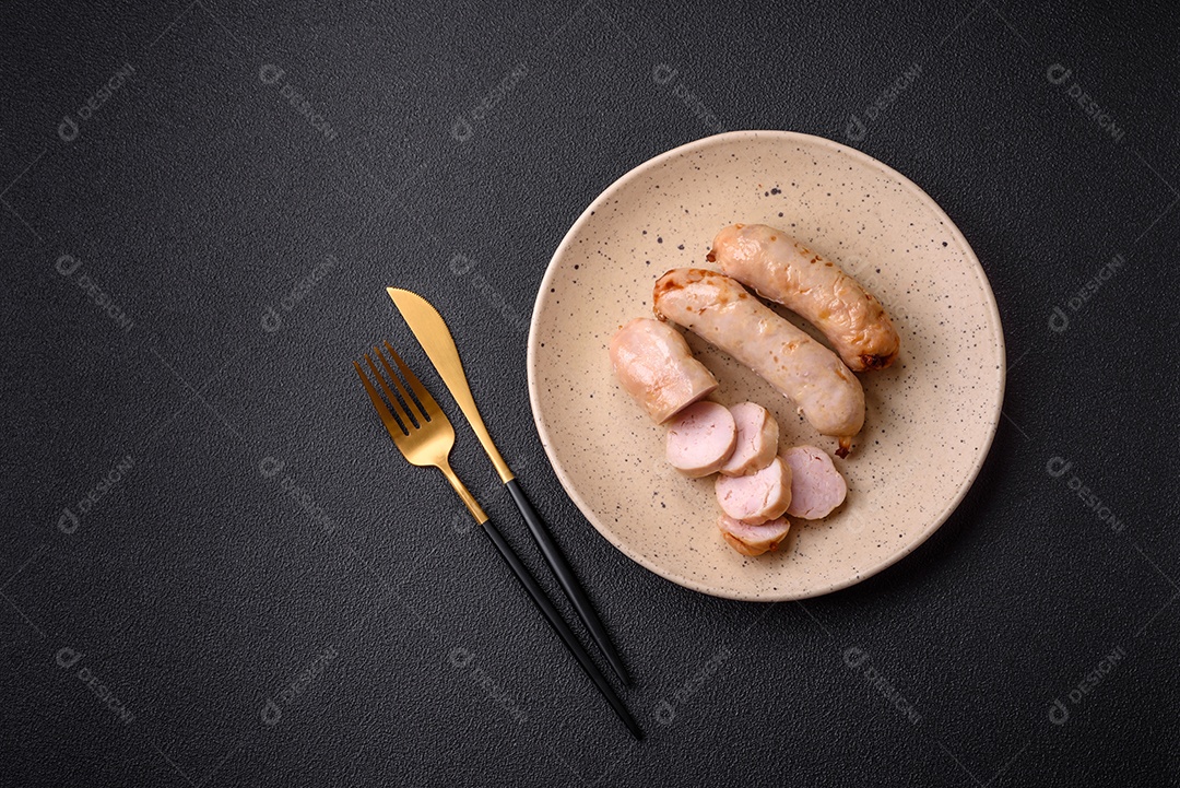 Deliciosos enchidos de frango ou porco grelhados com sal, especiarias e ervas sobre um fundo escuro de concreto