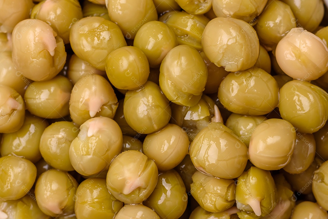 Deliciosas ervilhas enlatadas com sal e especiarias em uma tigela branca sobre um fundo escuro de concreto