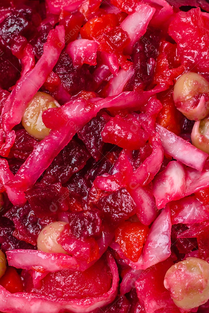 Deliciosa salada vinigret suculenta de legumes cozidos, batatas, beterraba, maconha, repolho e cenoura com sal e especiarias em um fundo escuro de concreto