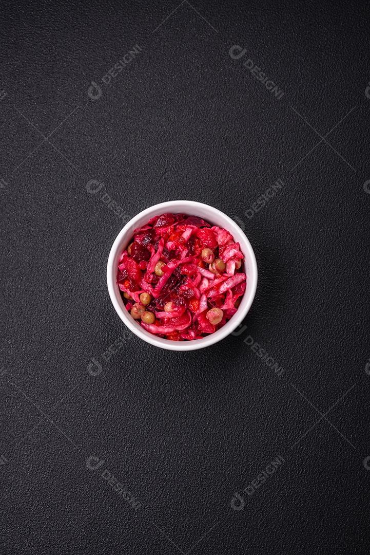 Deliciosa salada vinigret suculenta de legumes cozidos, batatas, beterraba, maconha, repolho e cenoura com sal e especiarias em um fundo escuro de concreto