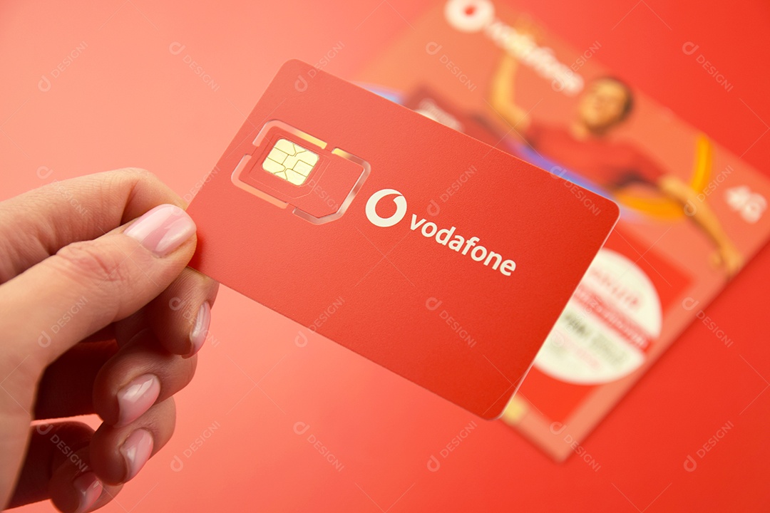 Pacote inicial da Vodafone em mão feminina sobre fundo vermelho