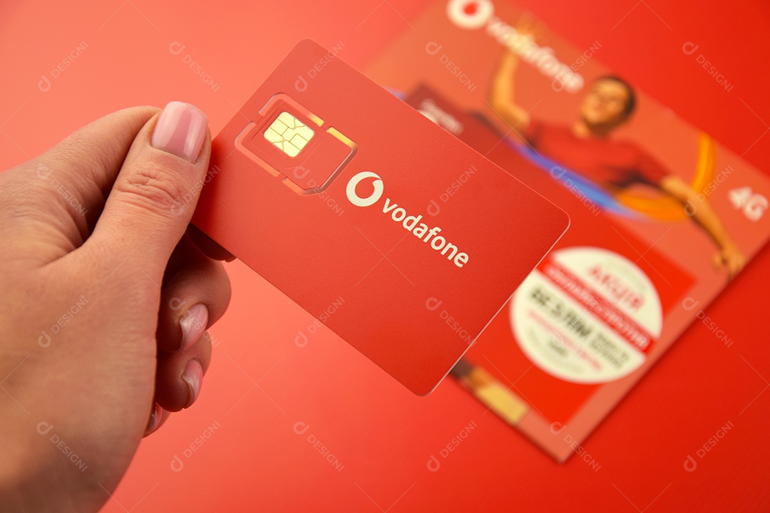 Pacote inicial da Vodafone em mão feminina sobre fundo vermelho