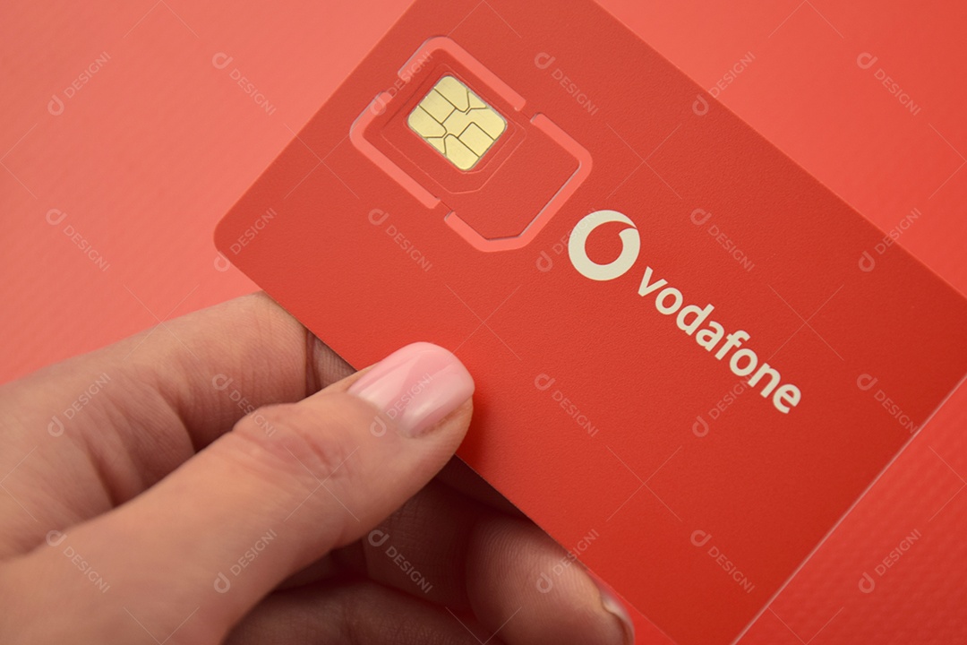 Pacote inicial da Vodafone em mão feminina sobre fundo vermelho