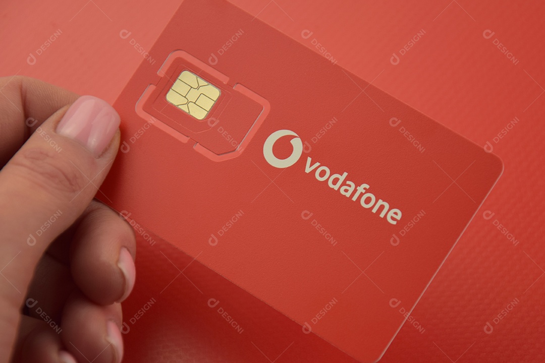 Pacote inicial da Vodafone em mão feminina sobre fundo vermelho