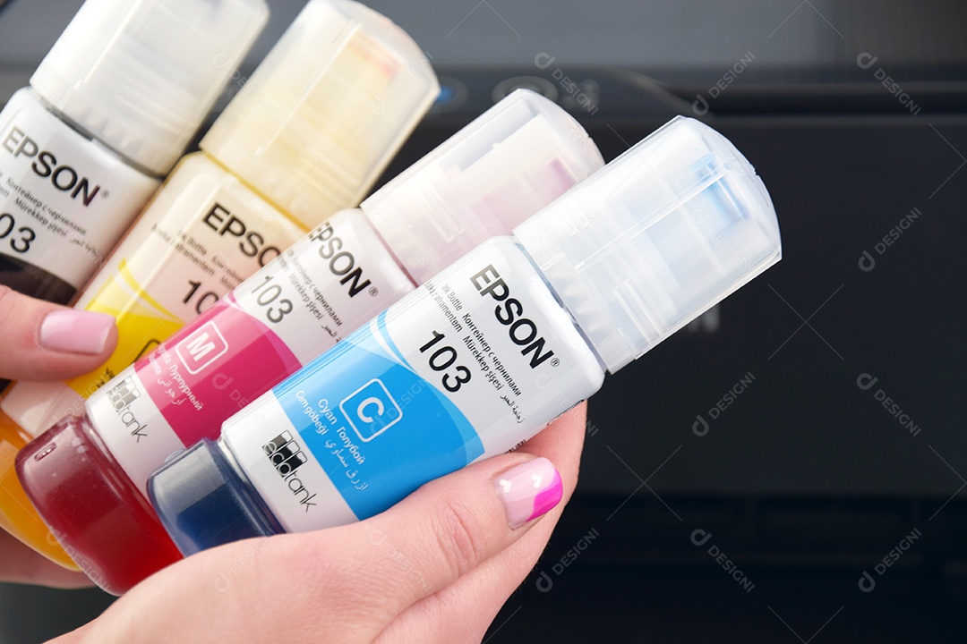 Quatro frascos de tinta Epson amarelo vermelho azul preto em mãos feminina