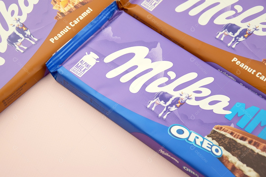 Marca de chocolate Milka com sabores Oreo e caramelo amendoim sobre fundo rosa suave