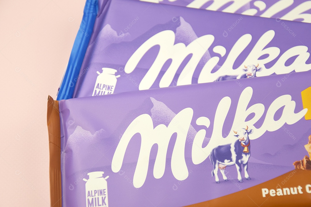 Marca de chocolate Milka com sabor Amendoim e caramelo sobre fundo rosa suave