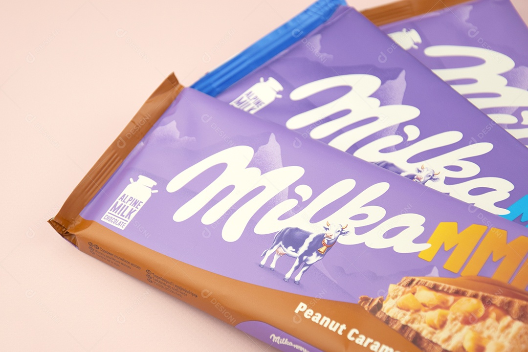 Marca de chocolate Milka com sabor Amendoim e caramelo sobre fundo rosa suave
