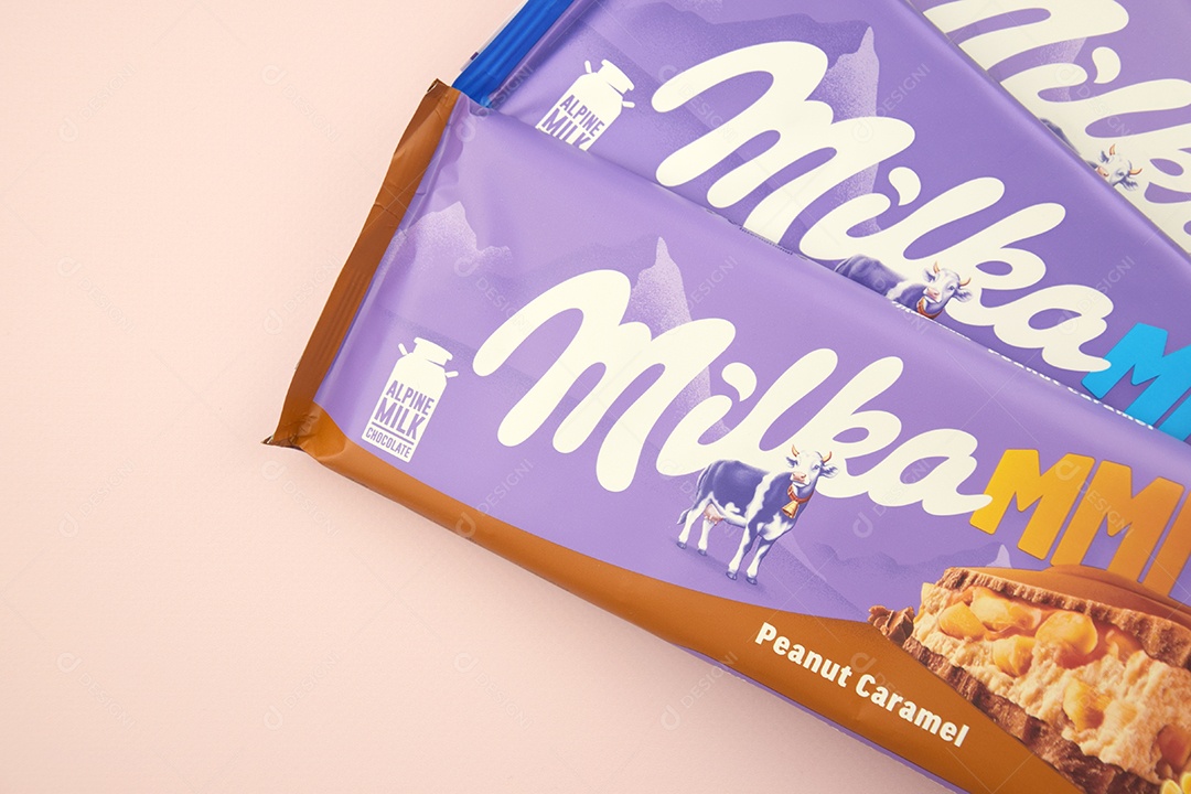 Marca de chocolate Milka com sabor Amendoim e caramelo sobre fundo rosa suave