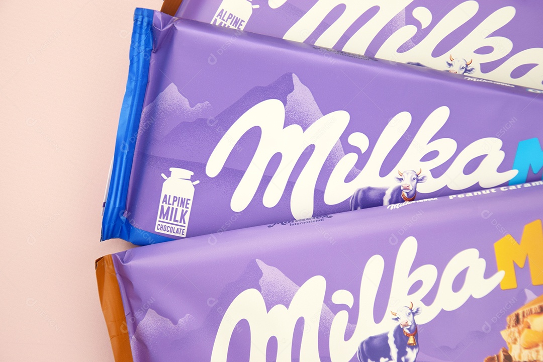 Marca de chocolate Milka com sabor Amendoim e caramelo sobre fundo rosa suave