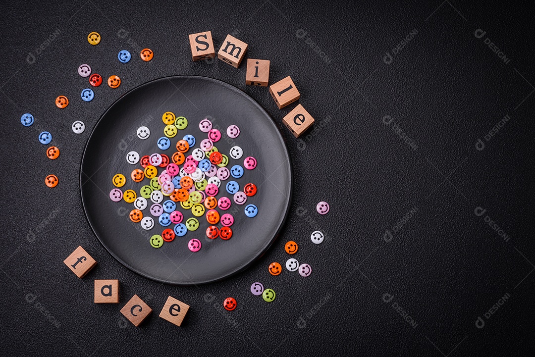 Conceito que consiste na inscrição da palavra sorriso, com emoticons redondos sobre fundo escuro de concreto. Pode ser usado como plano de fundo